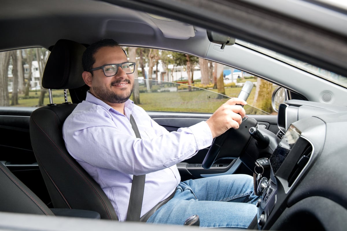 A man is driving a car with a smile on his face